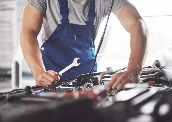 Picture showing muscular car service worker repairing vehicle.